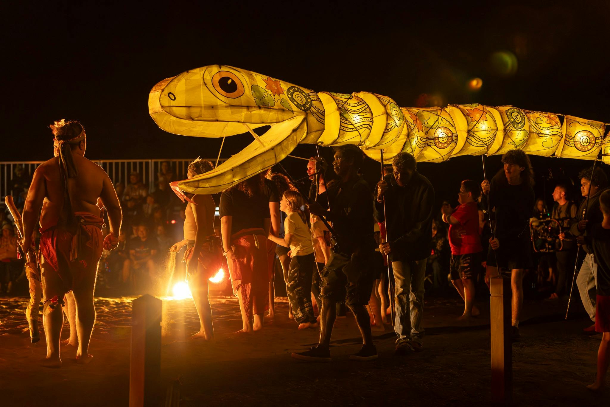 Large serpent puppet lantern amongst Indigenous dancers