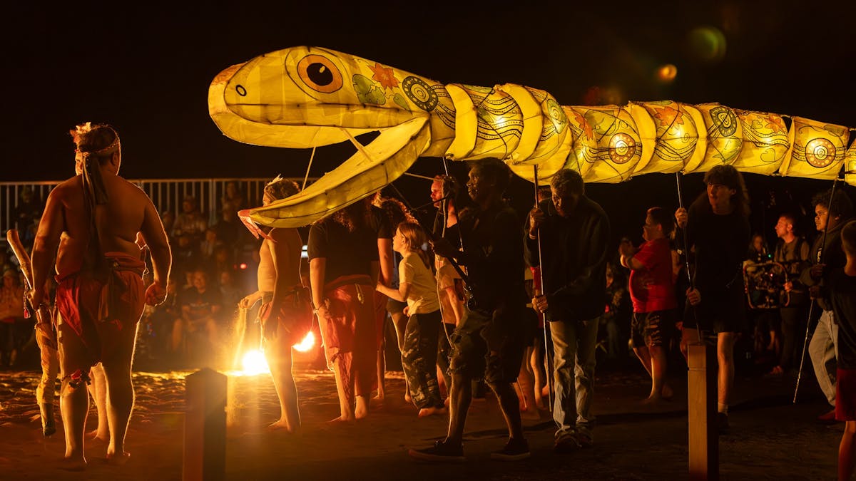 Large serpent puppet lantern amongst Indigenous dancers