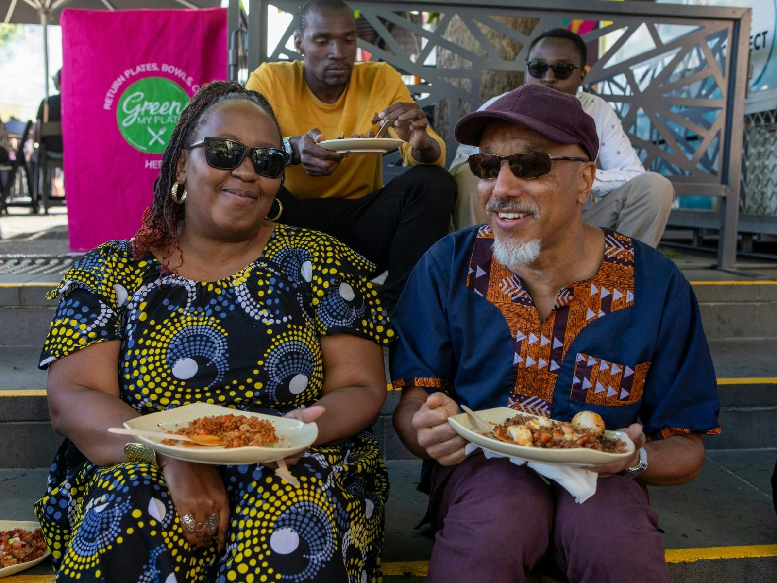 A couple sitting on a step eating African food