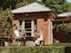 An image of friends sitting around a wine barrel in the sun on the front lawns of Elm Dining