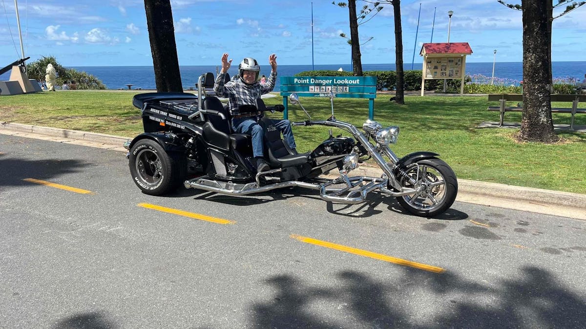 Image shows trike with one passenger in front of the beach.