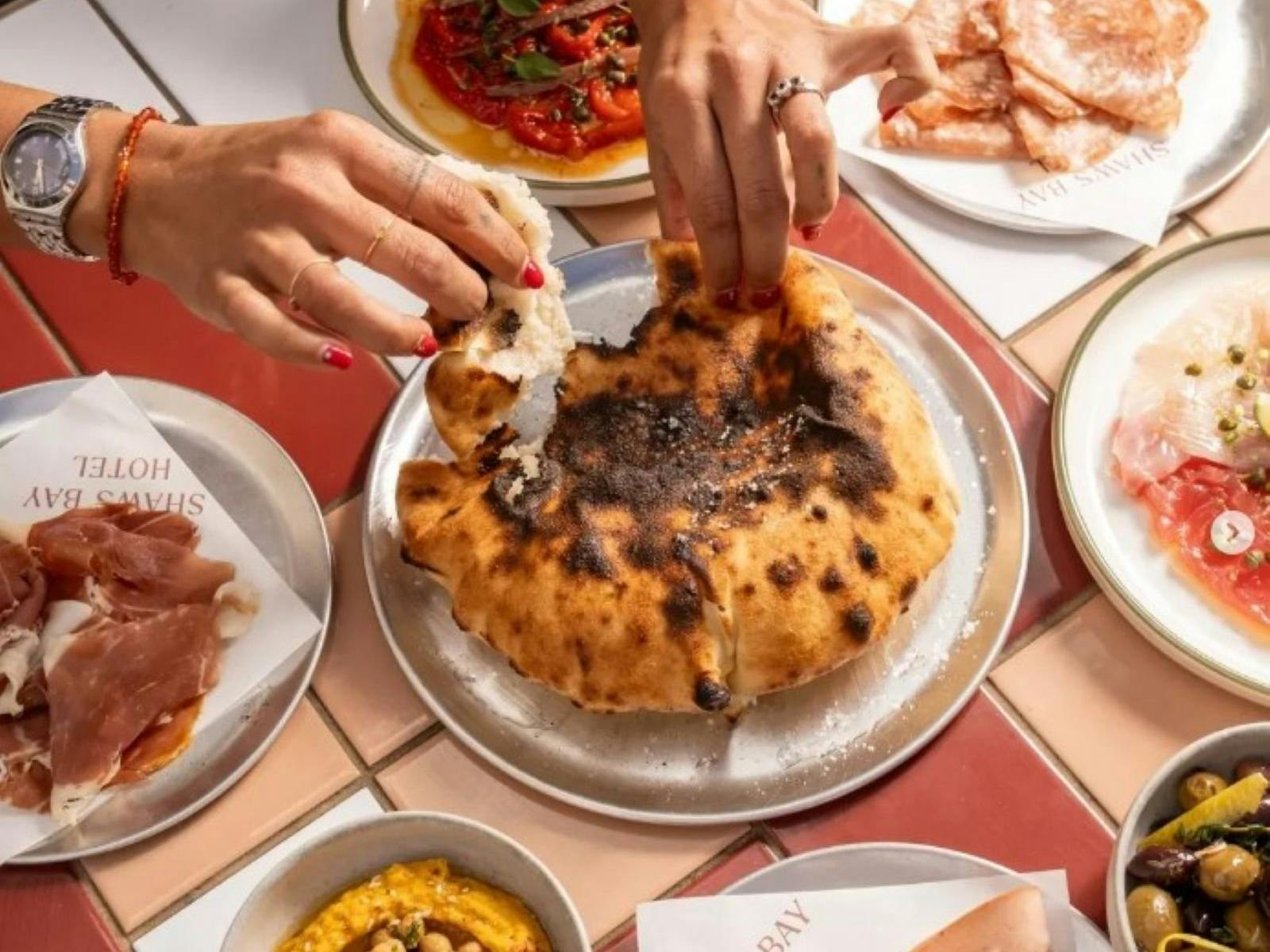share plates of bread, olives, meats