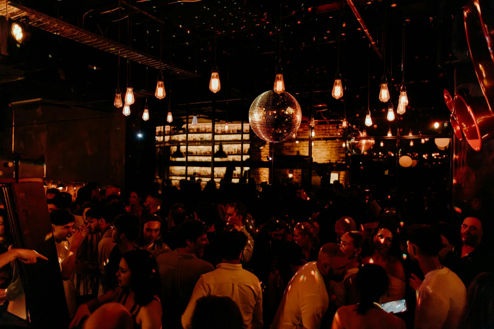 Gold Disco Ball is illuminated by glowing light bulbs under a red hue