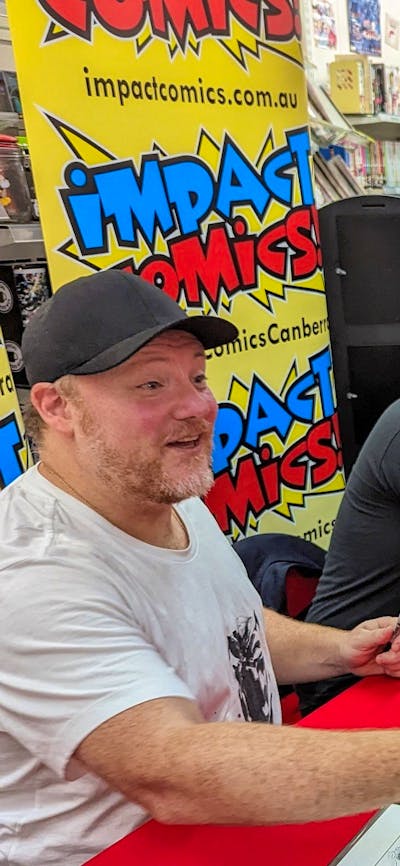 Two men sit at a table a line of people waiting to meet them