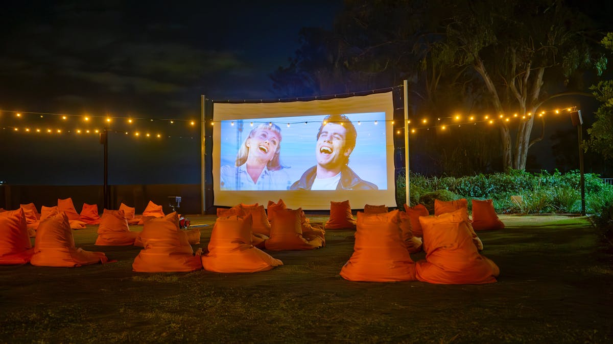 A image of a movie screening outside on the lawn with bean bags as a seating area with river views.