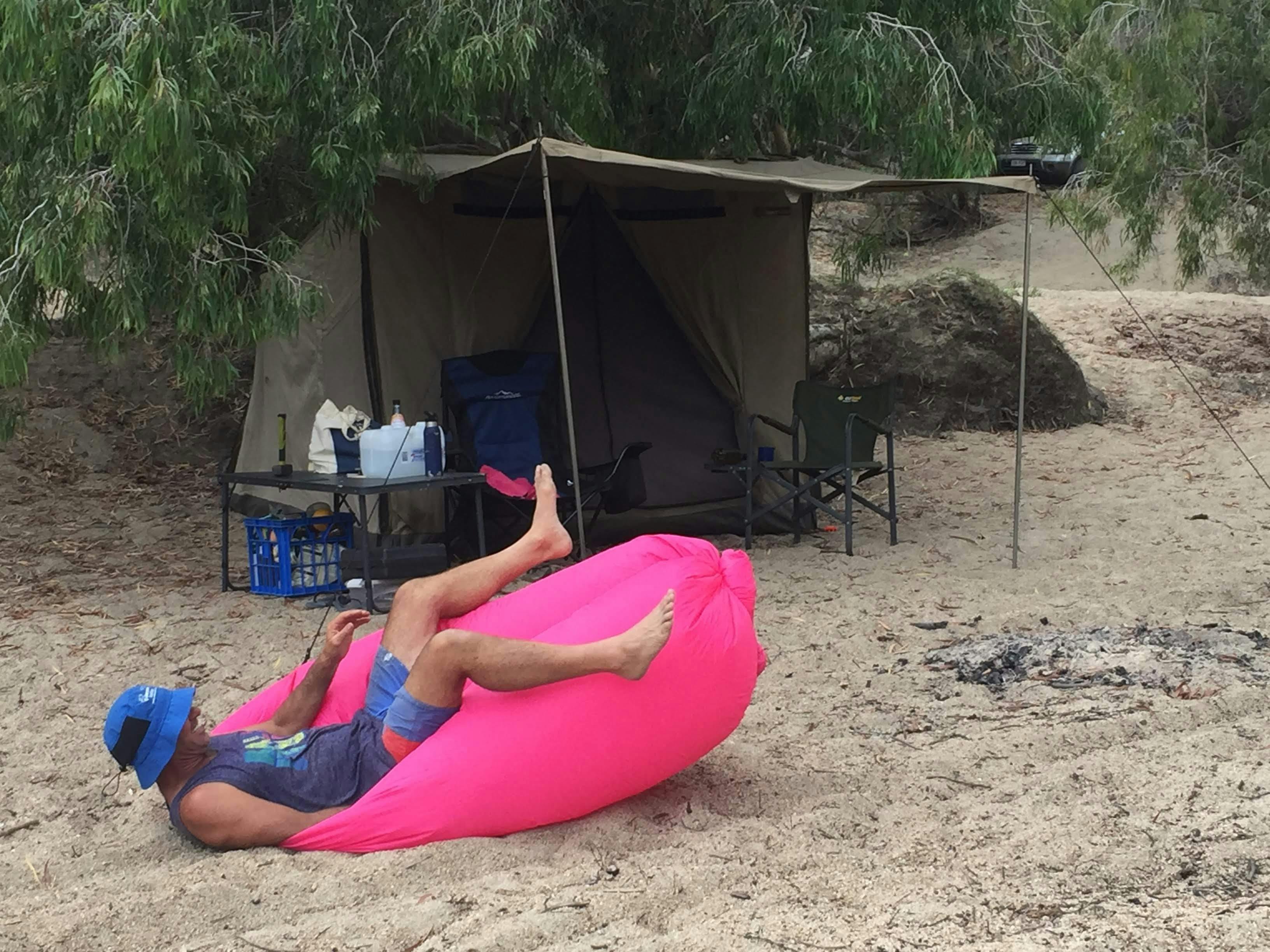 having fun on a bean bag on the sand, in front of a safari tent
