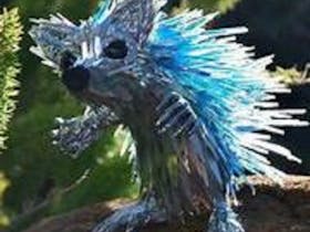 A rat made out of recycled materials. He has beady black eyes and light blue fur. He has little paws