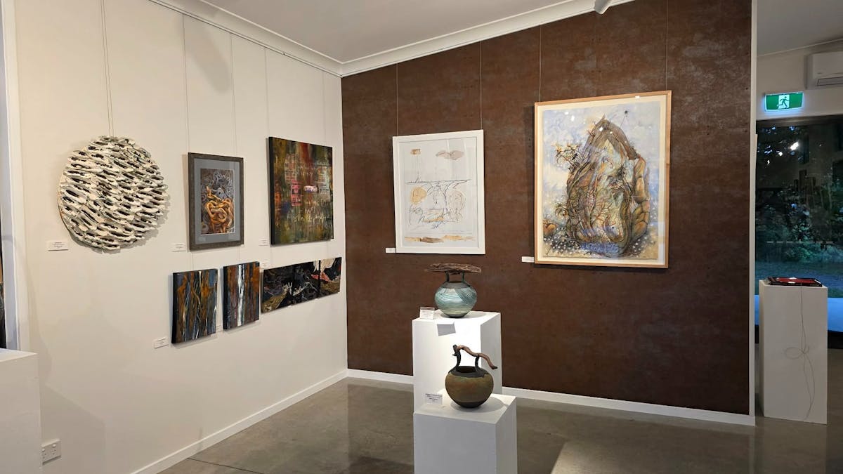 Artworks displayed on copper-look feature wall in art gallery