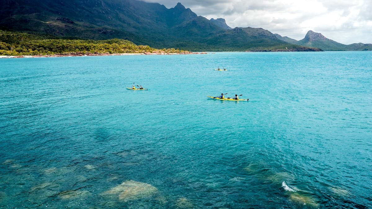 Mt Bowen & Nina Peak tower in the background as we paddle across a turquoise bay on Hinchinbrook