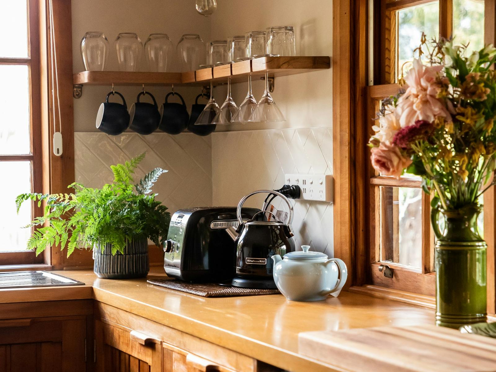 Photo of golden coloured wooden kitchen bench tops and shelf with assorted glassware