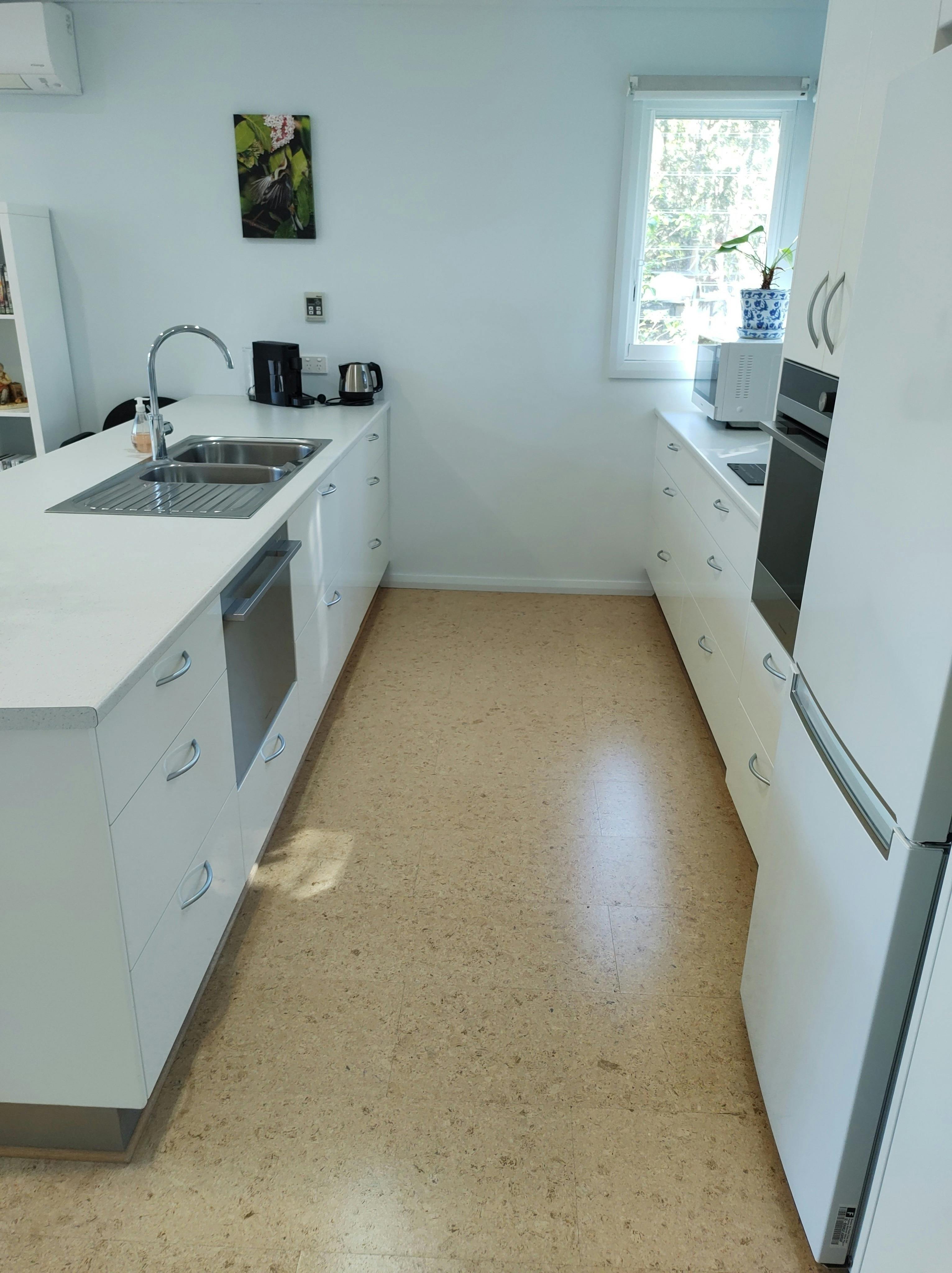 A fully equipped kitchen with dishwasher, microwave,  oven,  induction cooktop and under bench drawe