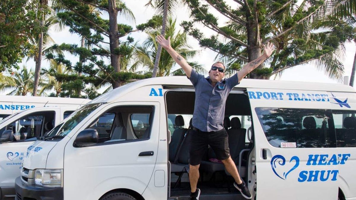 Heart of Reef Shuttles buses parked in a park with a man jumping from the doors