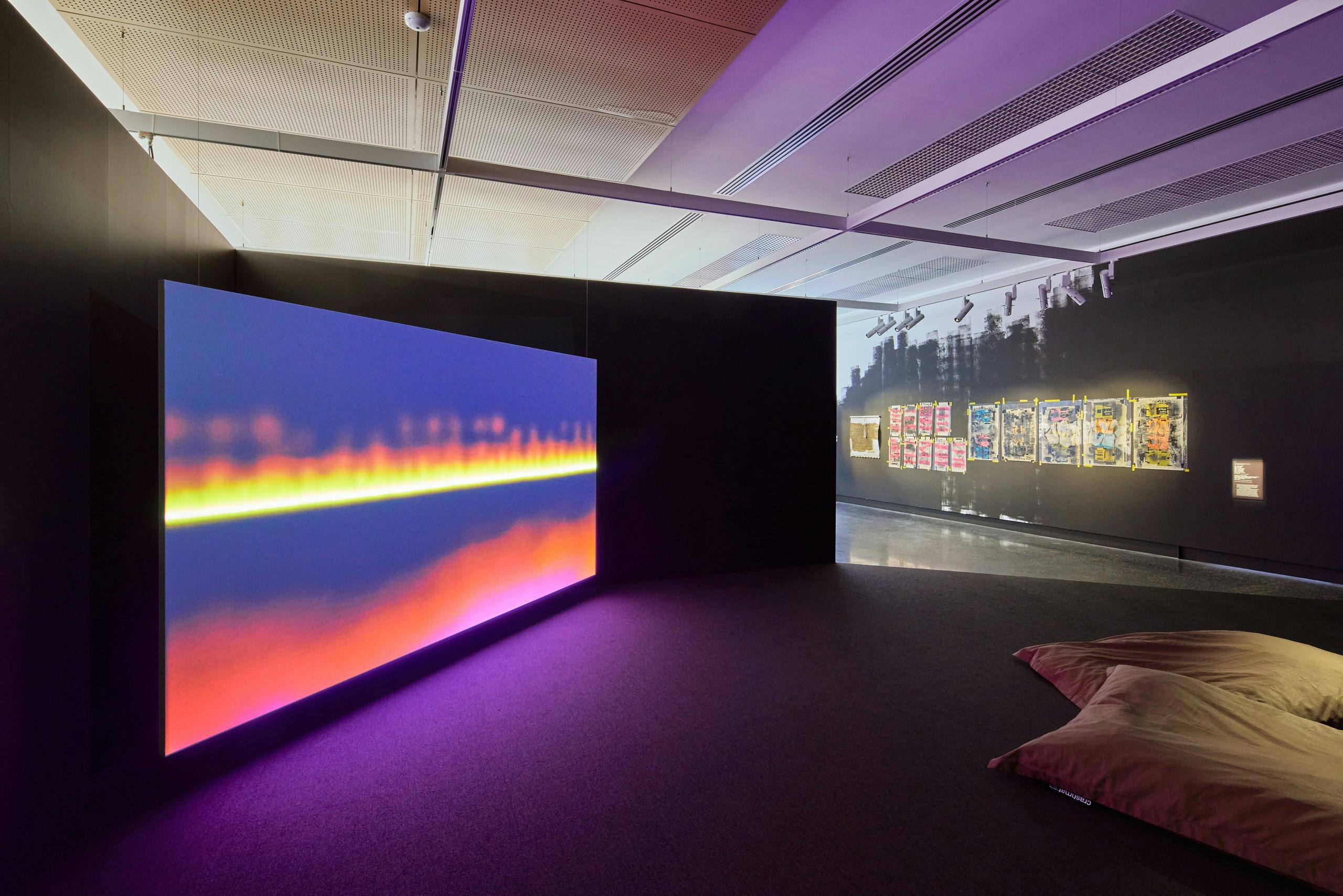 A large projection plays with red and yellow flames, two large cushions sit on the floor infront of