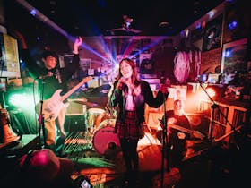A band performs in a brightly lit room, surrounded by colorful lights and vibrant music.