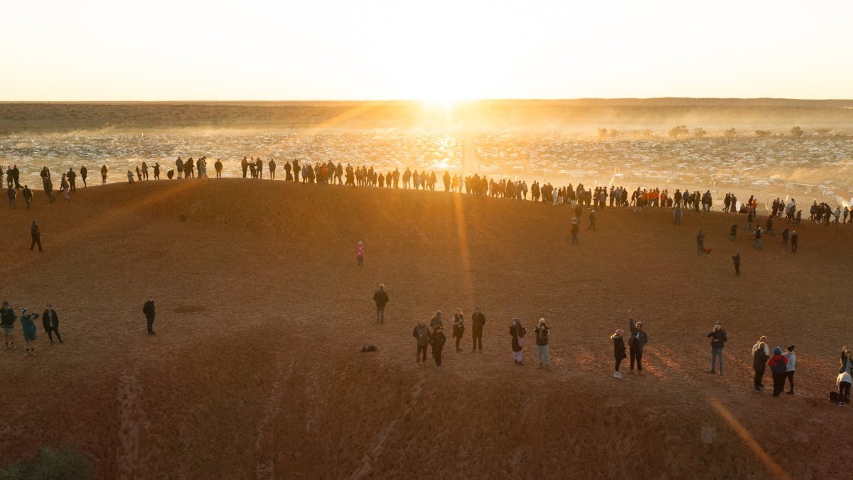 Dawn breaks over thousands of campers and caravans at the Birdsville Big Red Bash, Simpson Desert