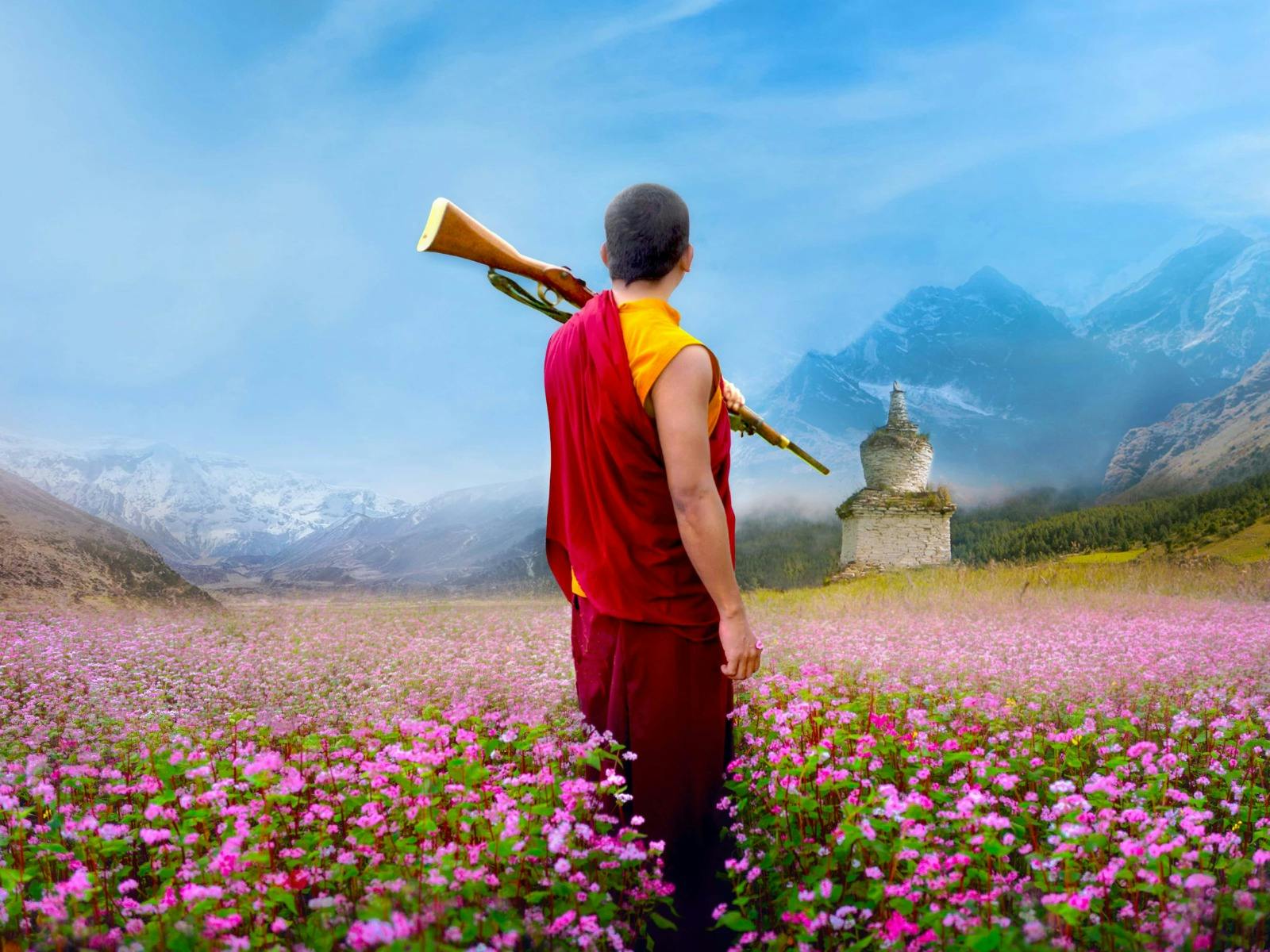 Mnk standing in a field of flowers  with a gun over his shoudler