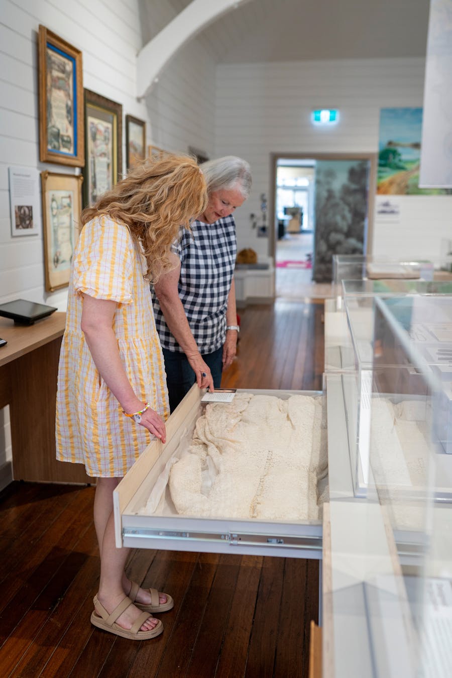 Two women looking at a historical dress laid out in a draw