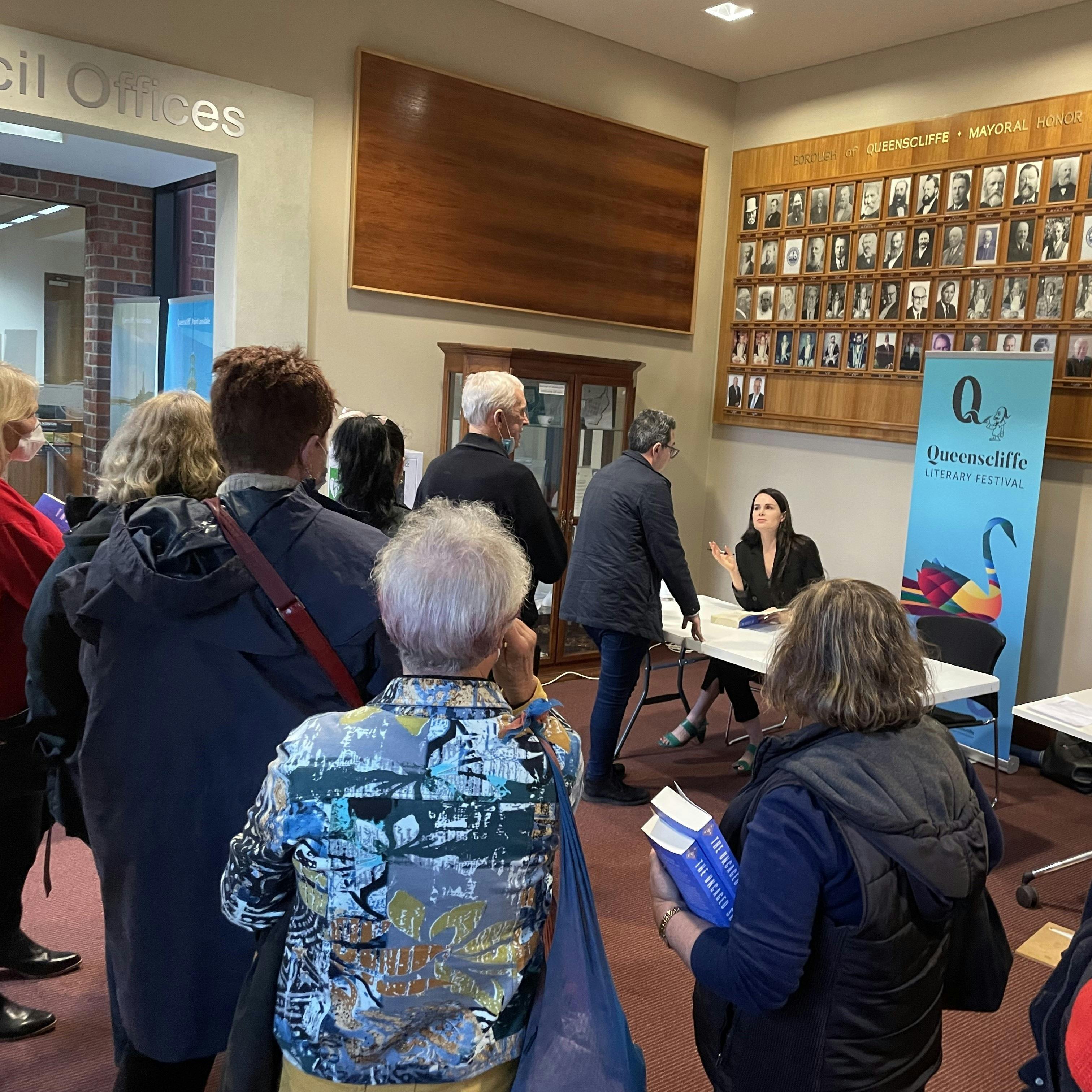Kylie Moore-Gilbert is seated to sign books; there is a long line of people waiting.