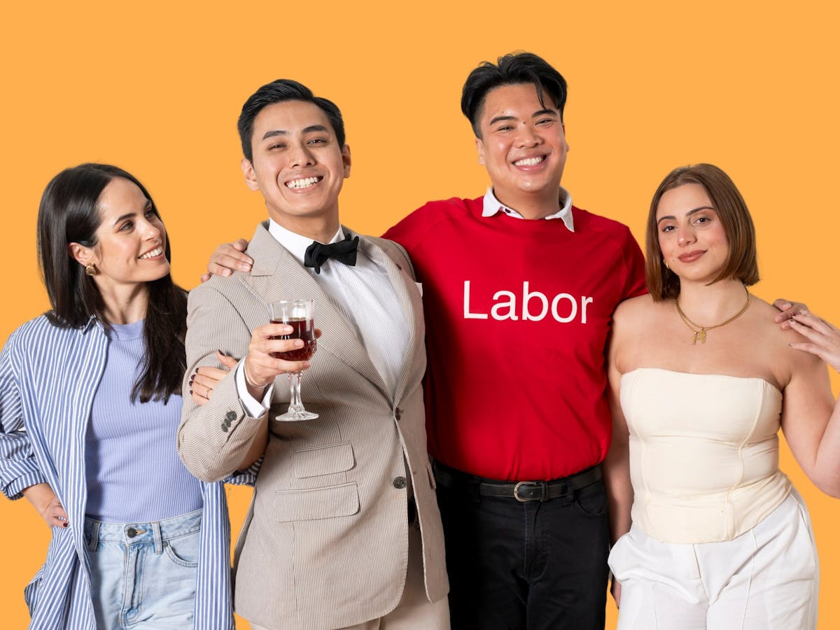 Four people smiling; orange background; one wears a “Labor” shirt, another holds a glass of red wine