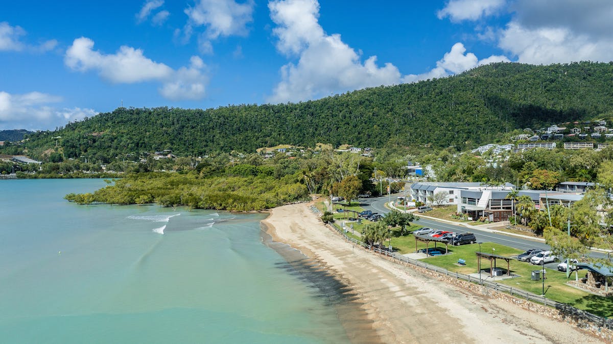 Aerial view of Cannonvale Beach with barbeque and parking areas along the foreshore