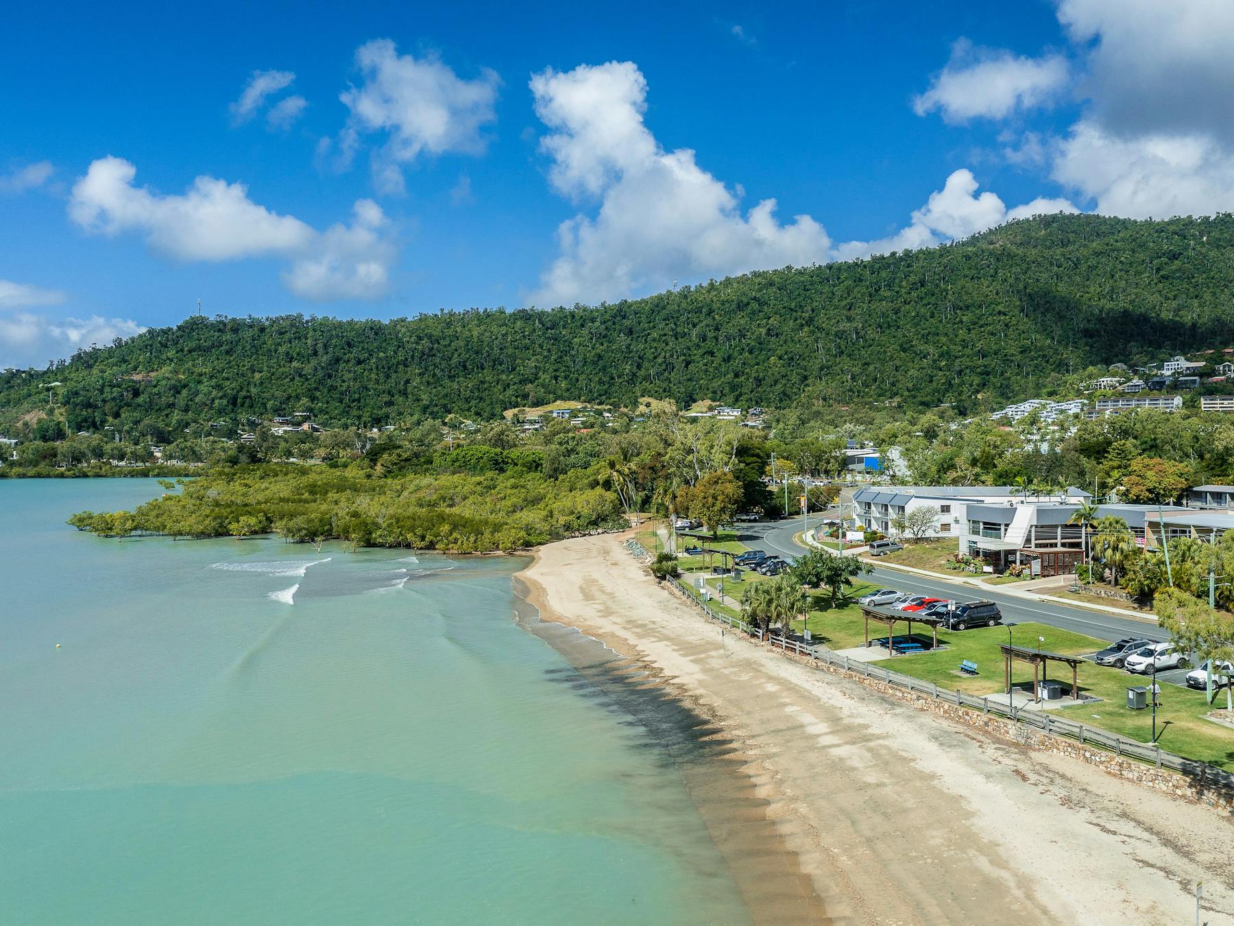 Aerial view of Cannonvale Beach with barbeque and parking areas along the foreshore