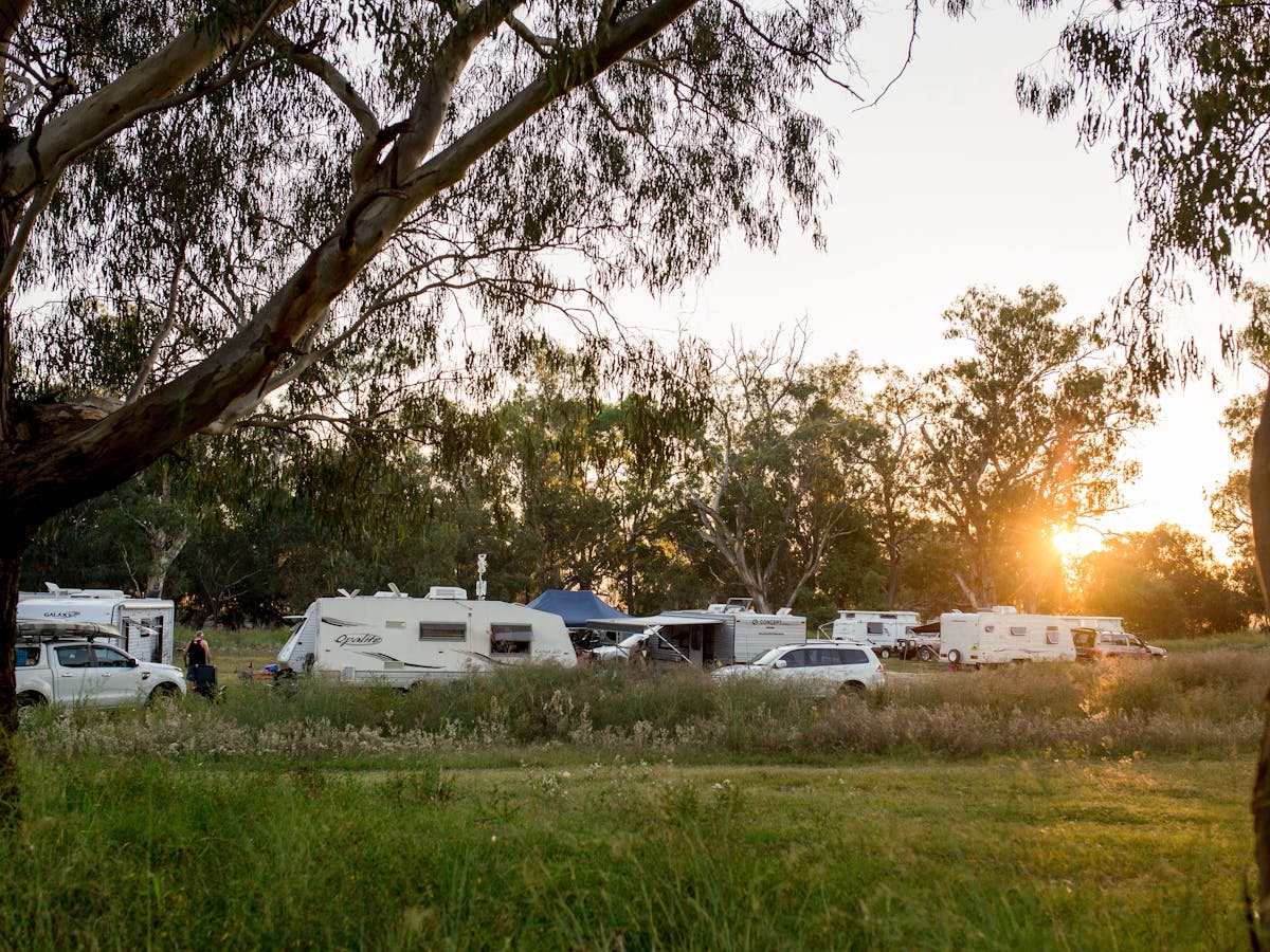 A group of caravans are parked at the Texas Free Camp Area as the sun is setting in the background A group of caravans are parked at the Texas Free Camp Area as the sun is setting in the background