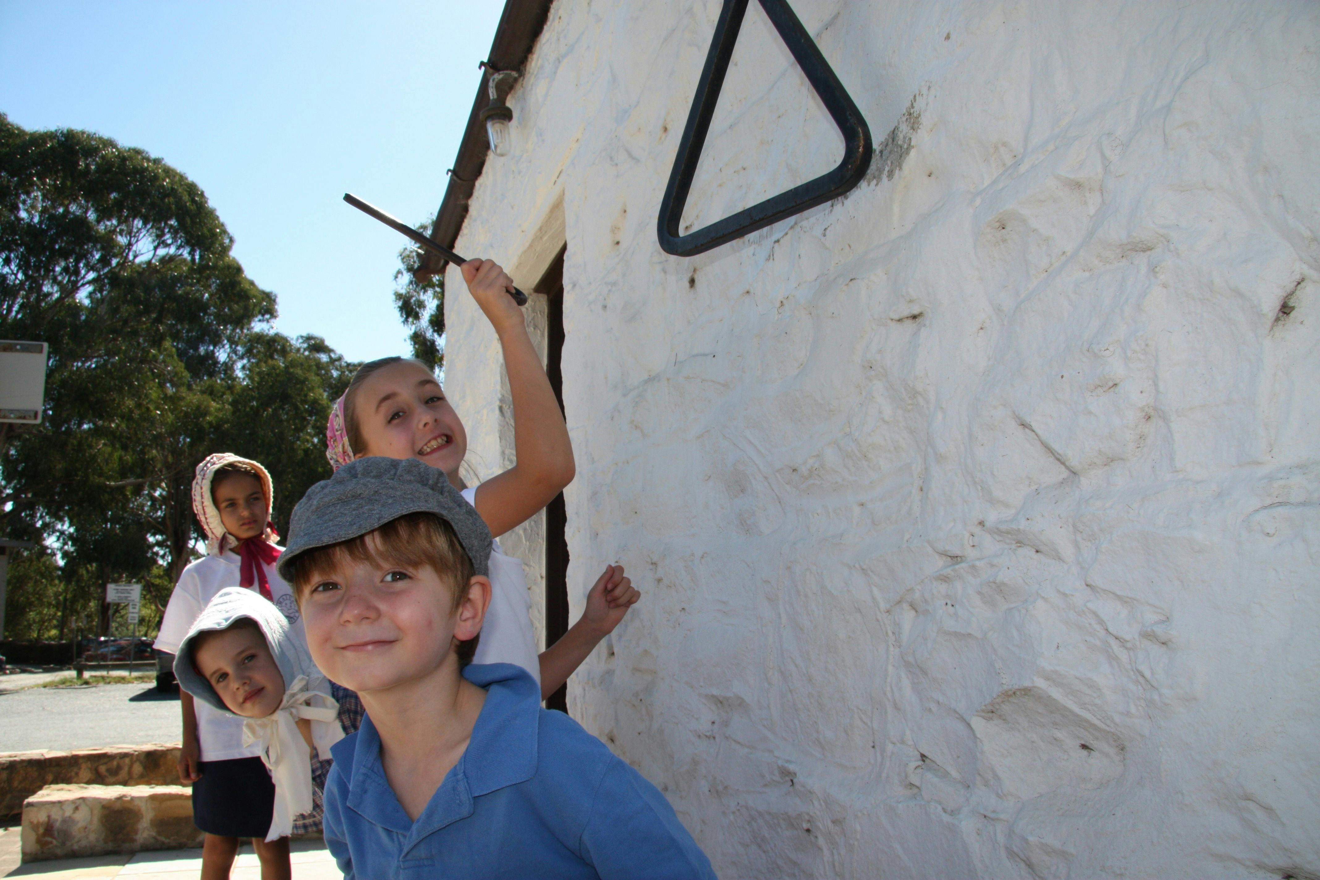 Four children in 18th century dress next to a white washed wall