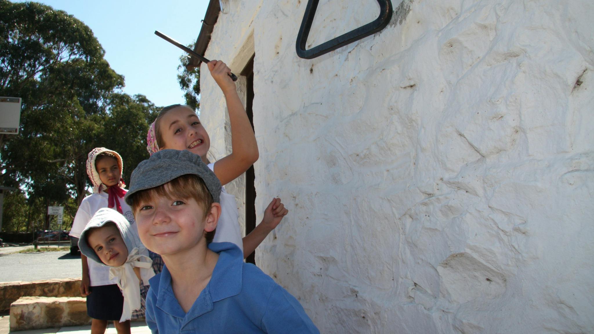 Four children in 18th century dress next to a white washed wall