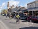 four cyclists riding beside historic shop fronts