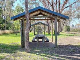 Two picnic table shelters with gum trees behind them.