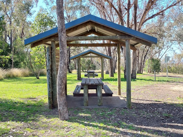 Two picnic table shelters with gum trees behind them.