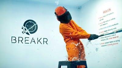 Someone in protective gear, smashing glass with a bat