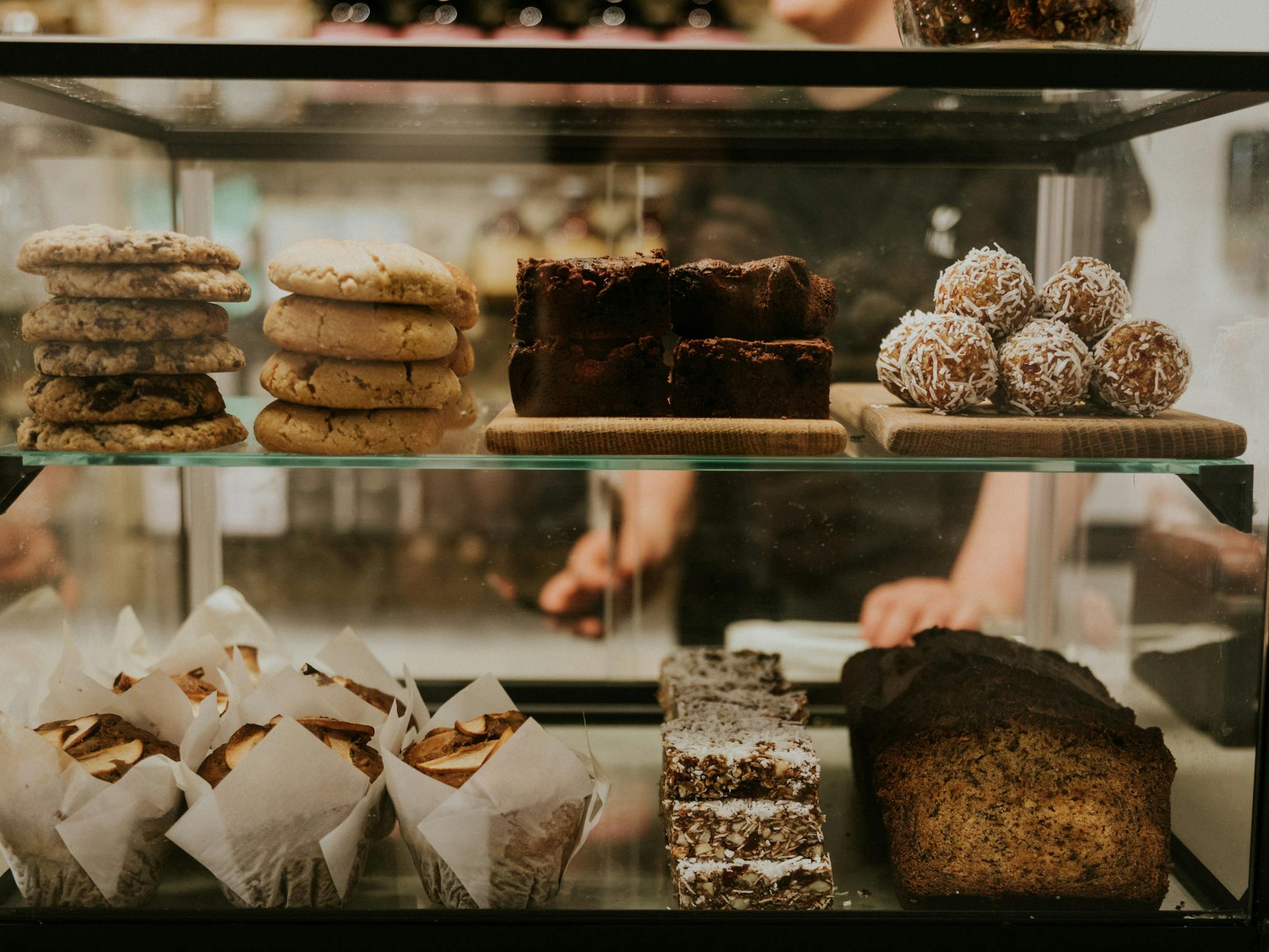 Glass pastry case loaded with cookies, muffins, banana bread, muesli bars
