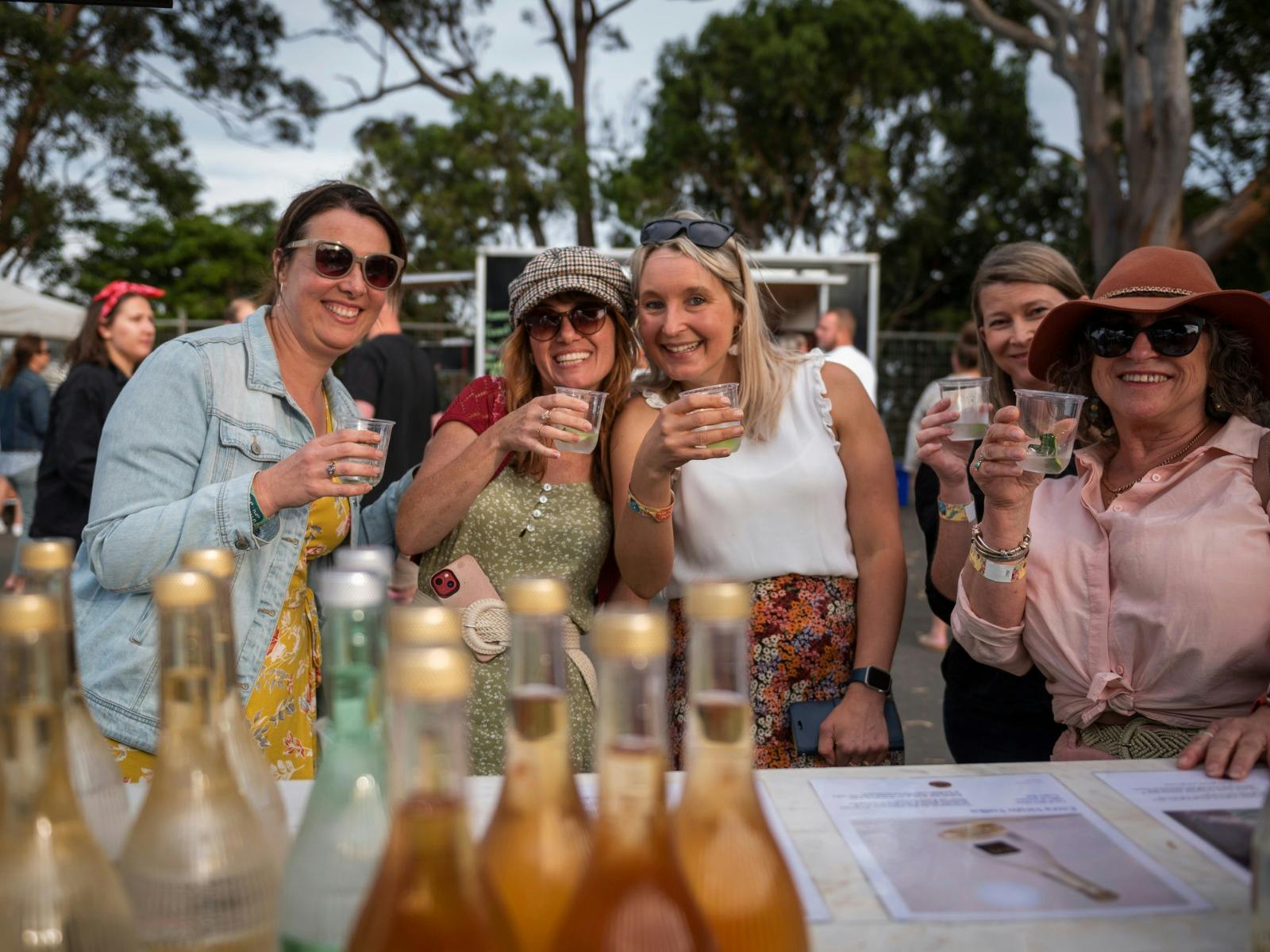 Group of guests posing in front of a local distiller’s stall at the Spirits of Jervis Bay Festival