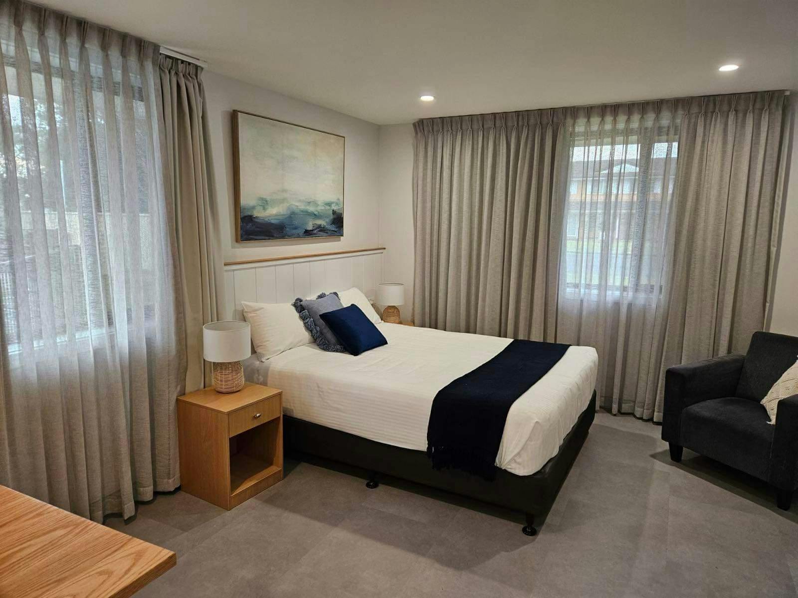 interior of room with white doona, blue cushions, curtains and framed picture