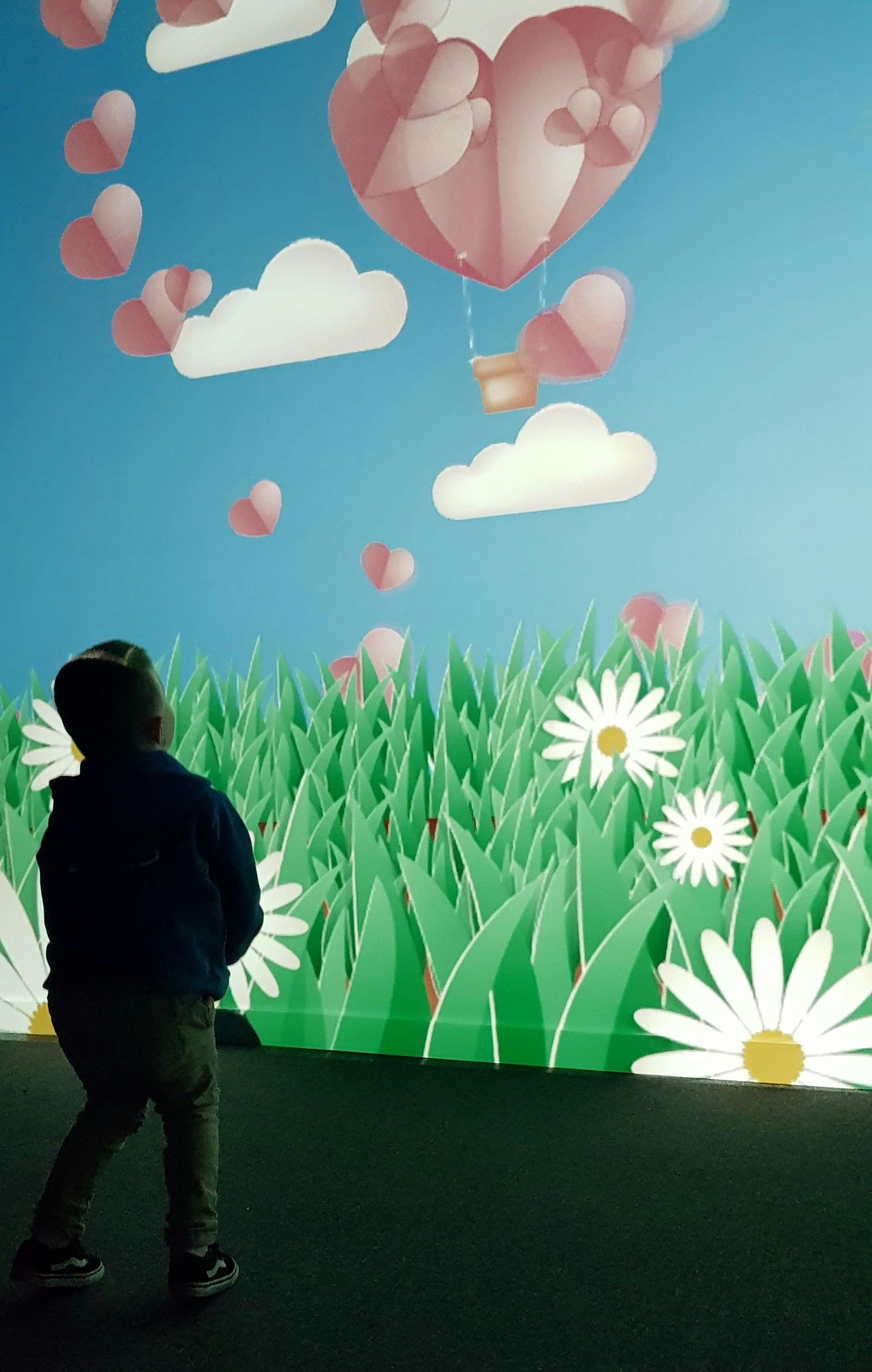 Young child moving his body to interact with a large-format digital game projected onto a wall.