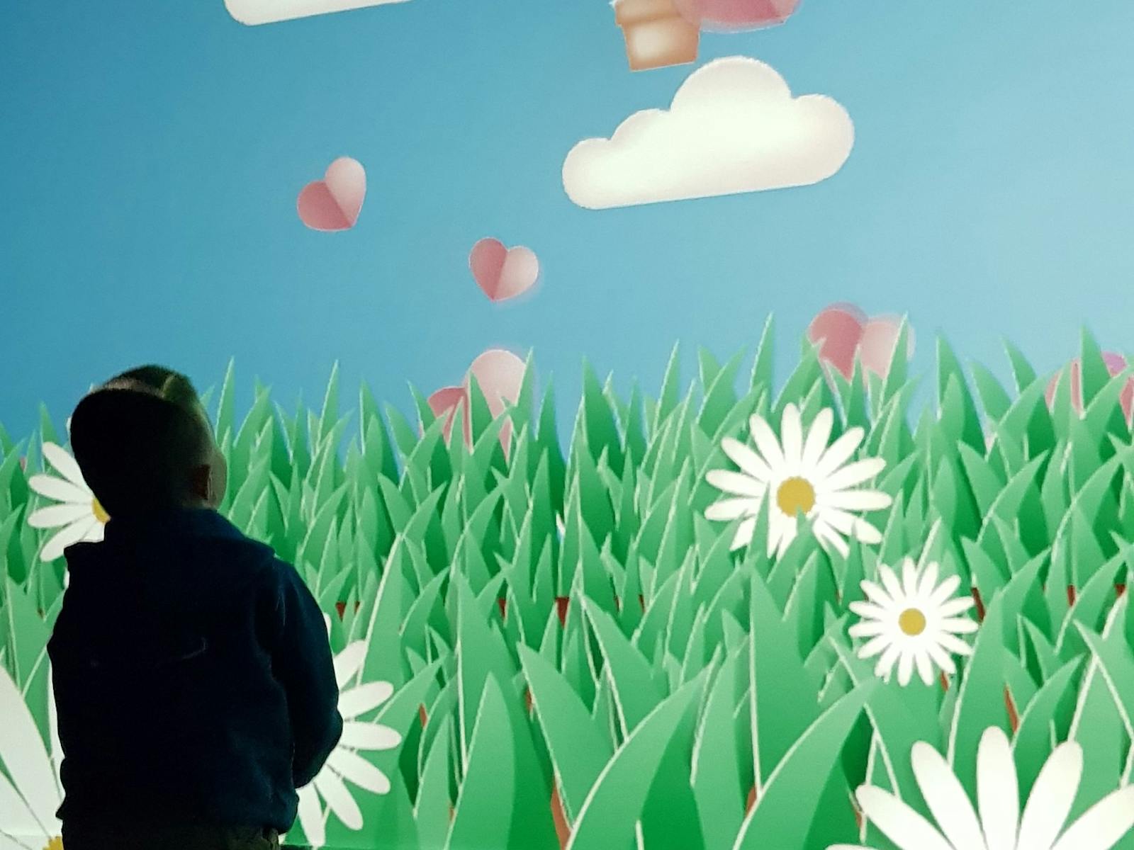 Young child moving his body to interact with a large-format digital game projected onto a wall.