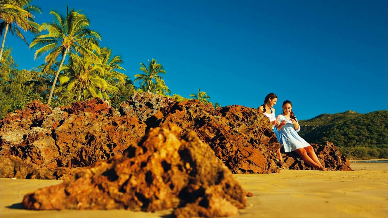 Mother and daughter sitting on rocks along Cape Hillsborough beach