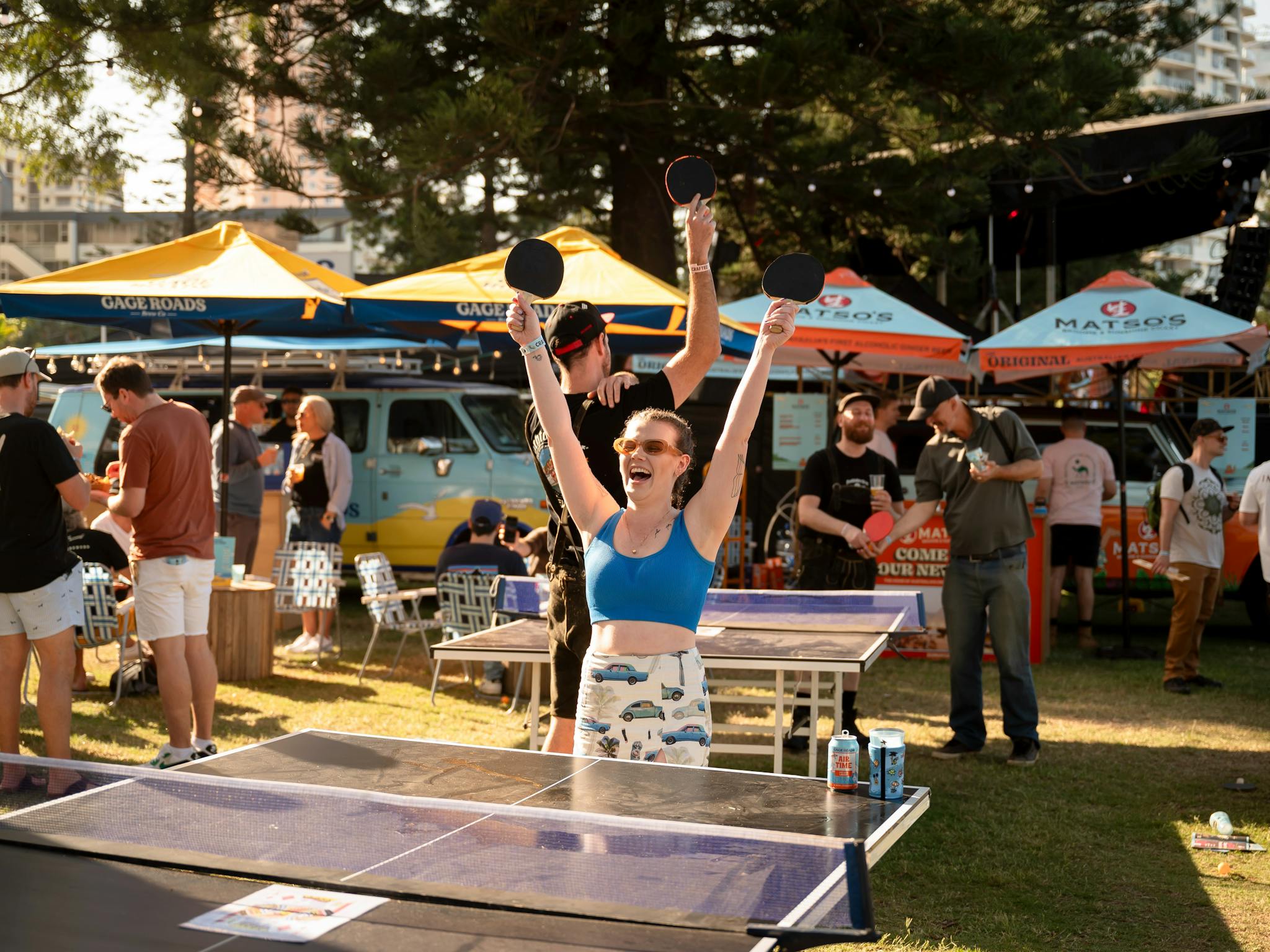 A girl throws her hands in the air to celebrate while playing a game of ping pong