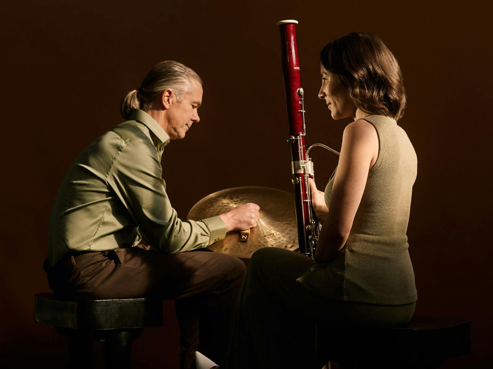 A photo of two orchestra players with their instruments, facing each other, away from the camera