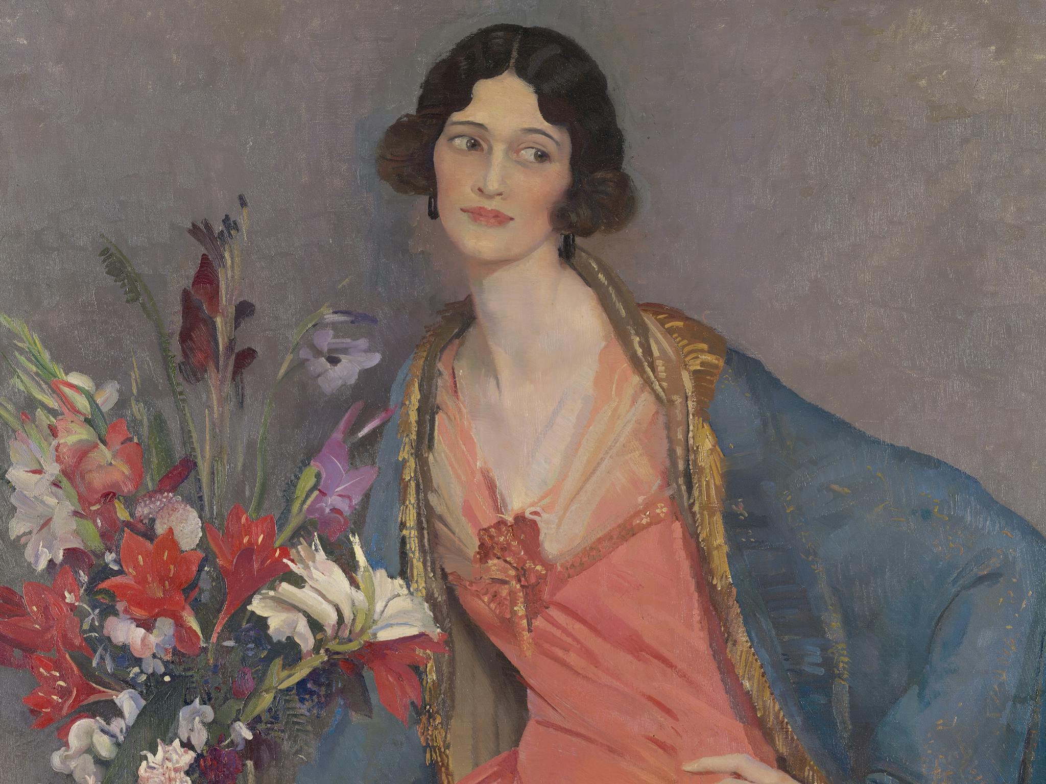 woman with short dark hair, standing next to a vase of flowers