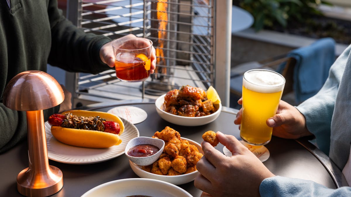 Men enjoying a beer, a negroni and winter food bites next to the fire, at Hibiscus Bar & Terrace