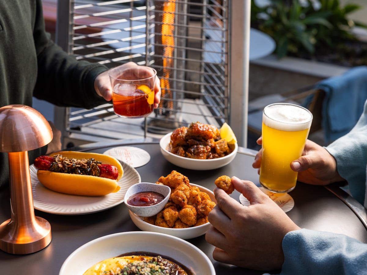 Men enjoying a beer, a negroni and winter food bites next to the fire, at Hibiscus Bar & Terrace