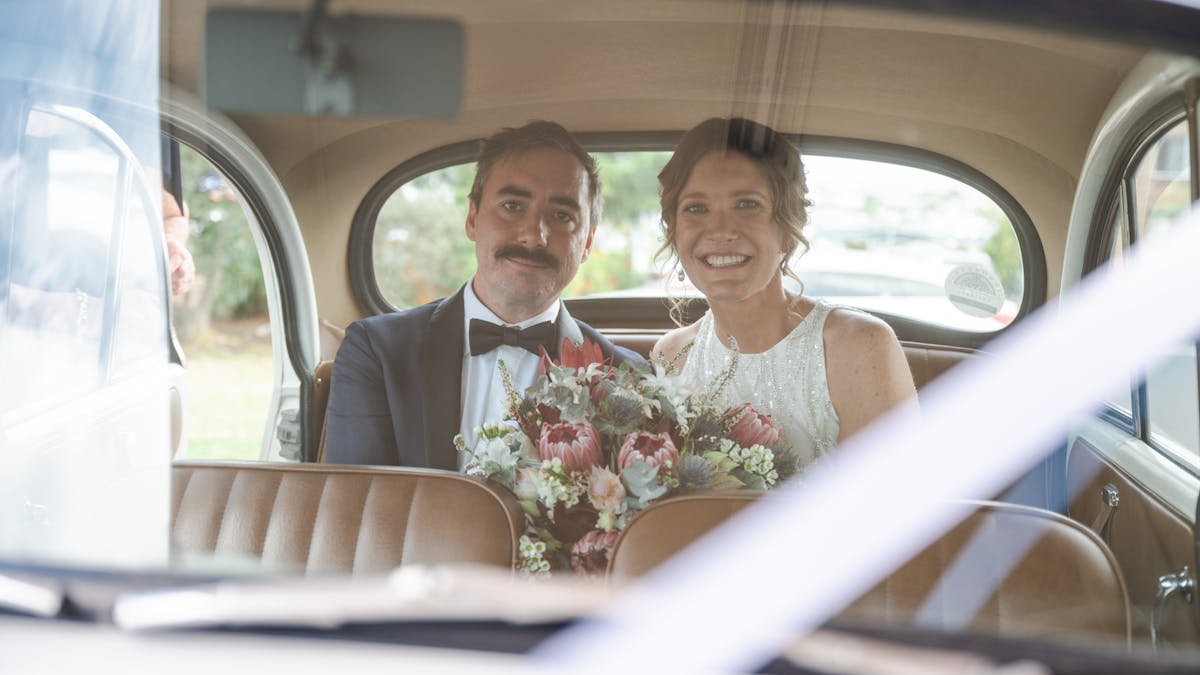 Bridge and Groom sitting in the back seat of Vintage Tours Morris Minor