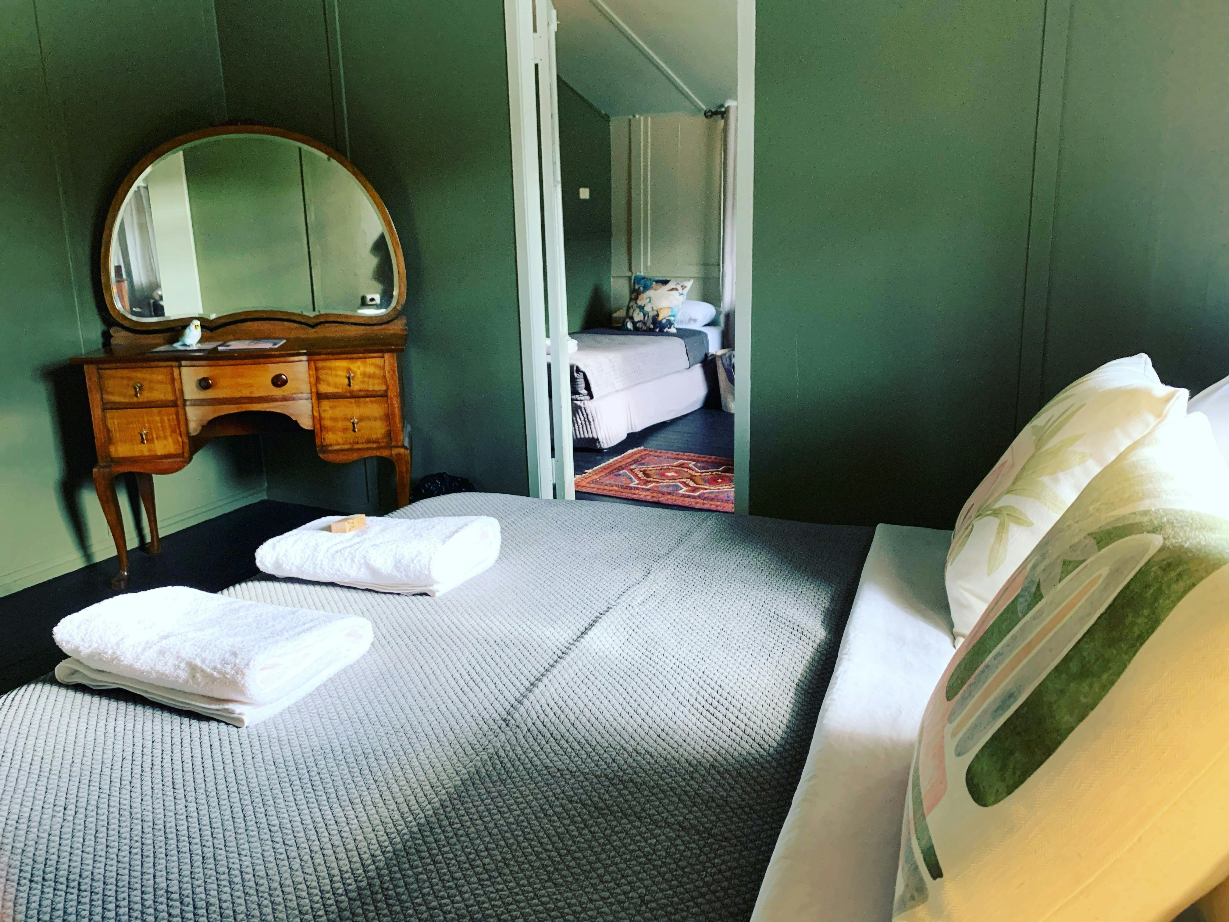 Hotel room with Bed made up with grey cover and wooden dressing table