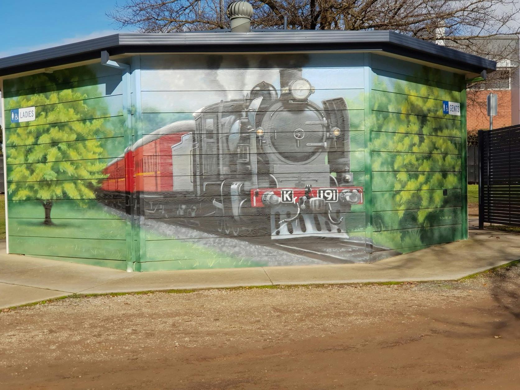 Painting of Steam train with black engine and red carriages and trees on toilet block in Wangaratta