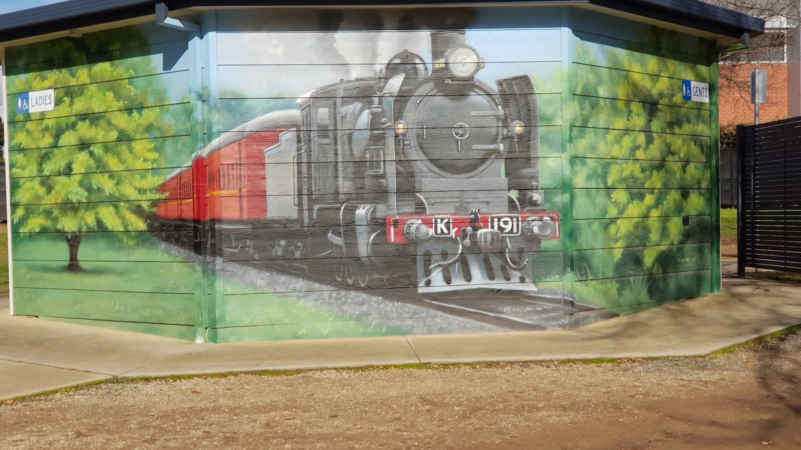 Painting of Steam train with black engine and red carriages and trees on toilet block in Wangaratta