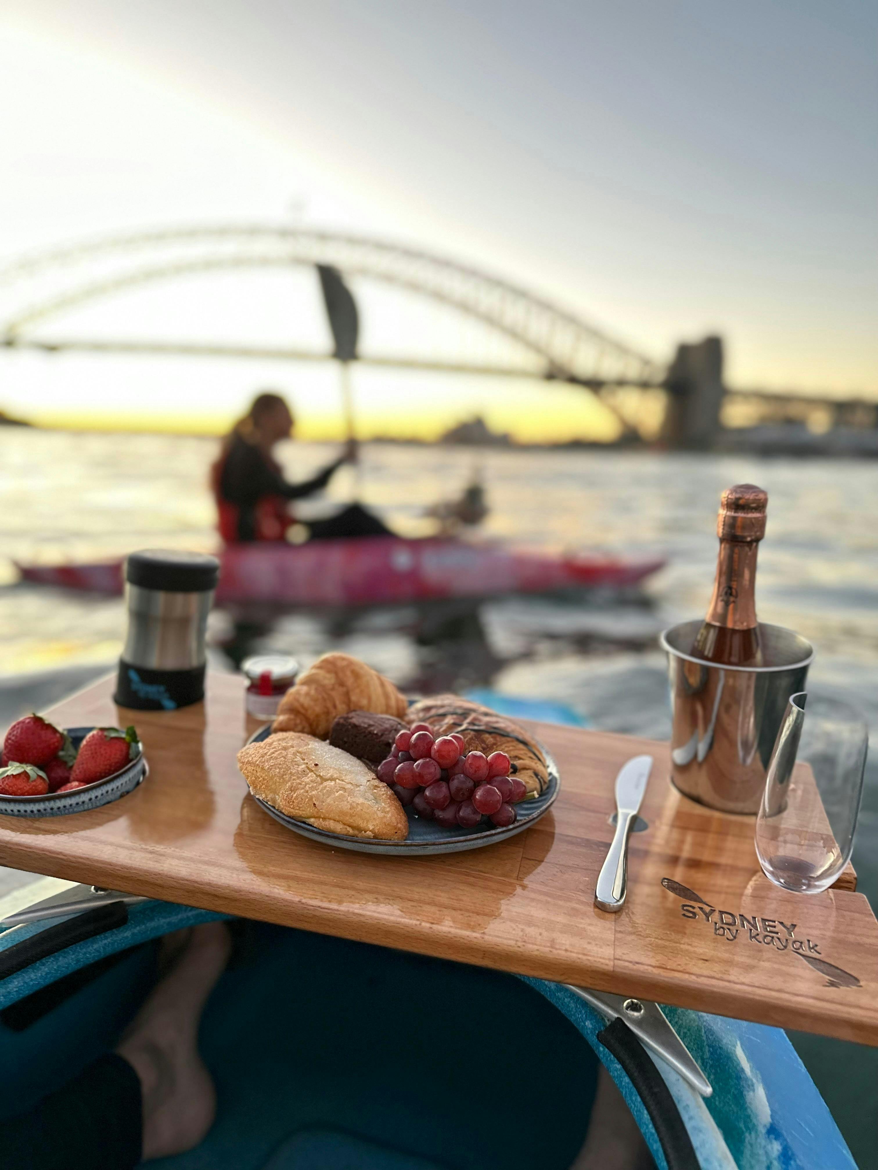 Champagne Breakfast with Sydney By Kayak is on display while kayking in front of harbour bridge.