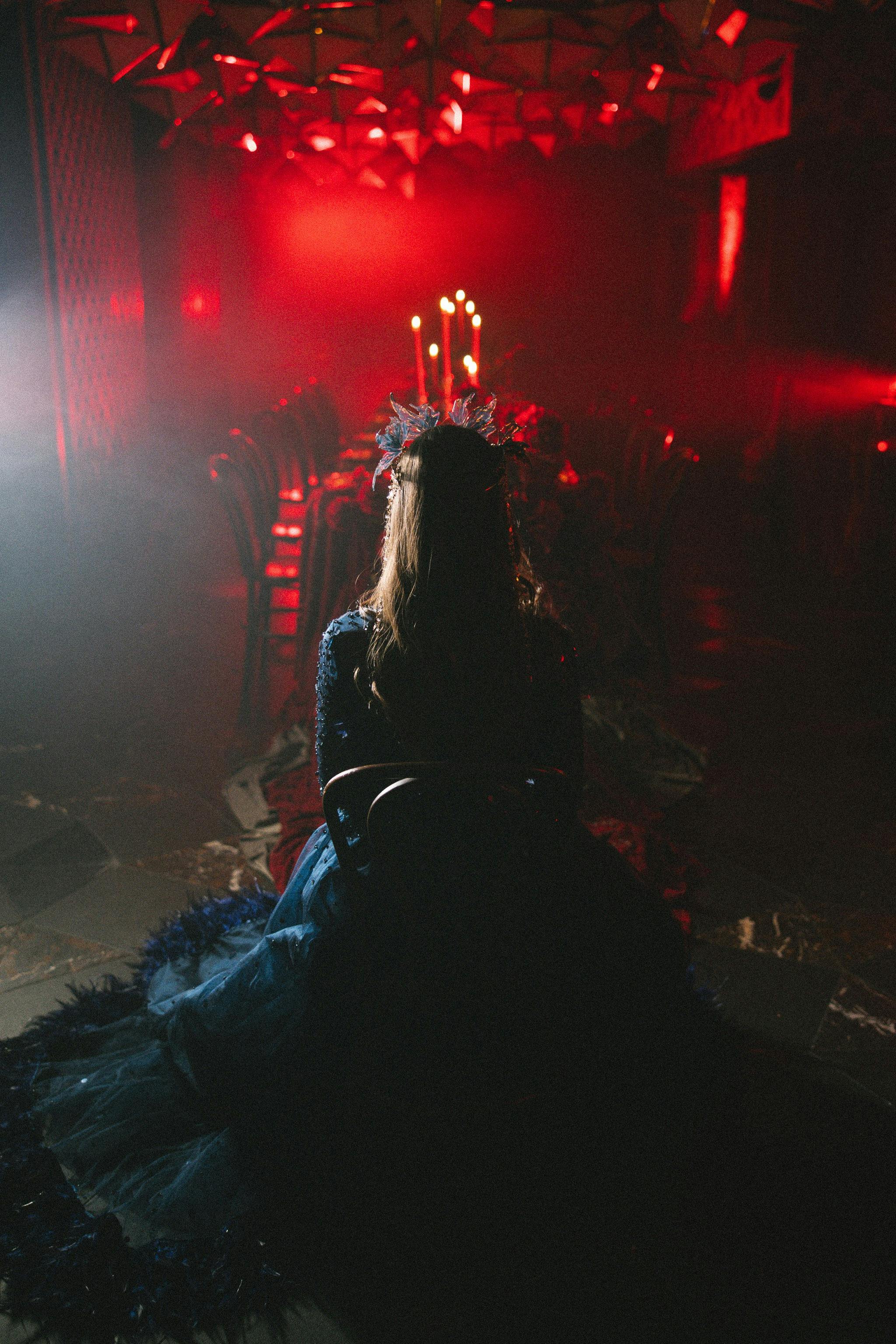 A character sitting with her back to the frame, overlooking a banquet table