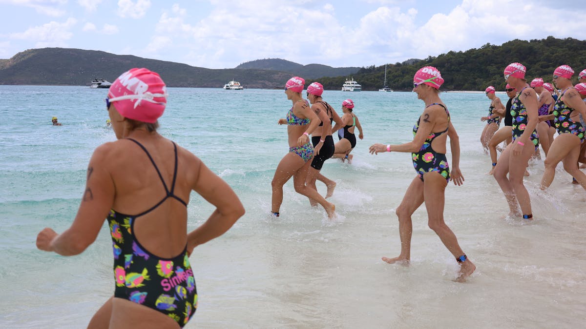 action photo of 1km female swimmers running into the water at the beginning of race